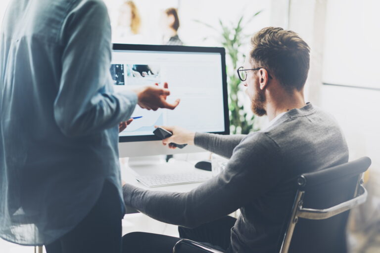 Photo of two people discussing a project in front of a computer.